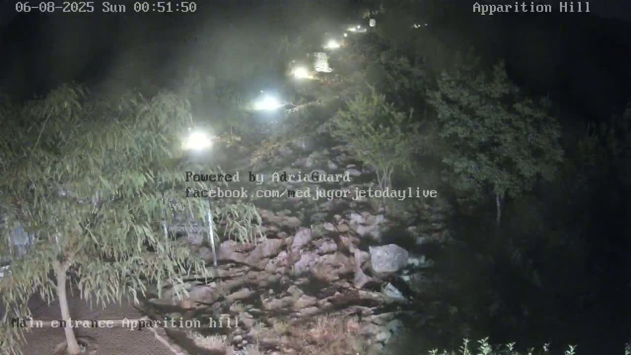 A nighttime view of a rocky area with vehicles visible in the distance, under hazy conditions.