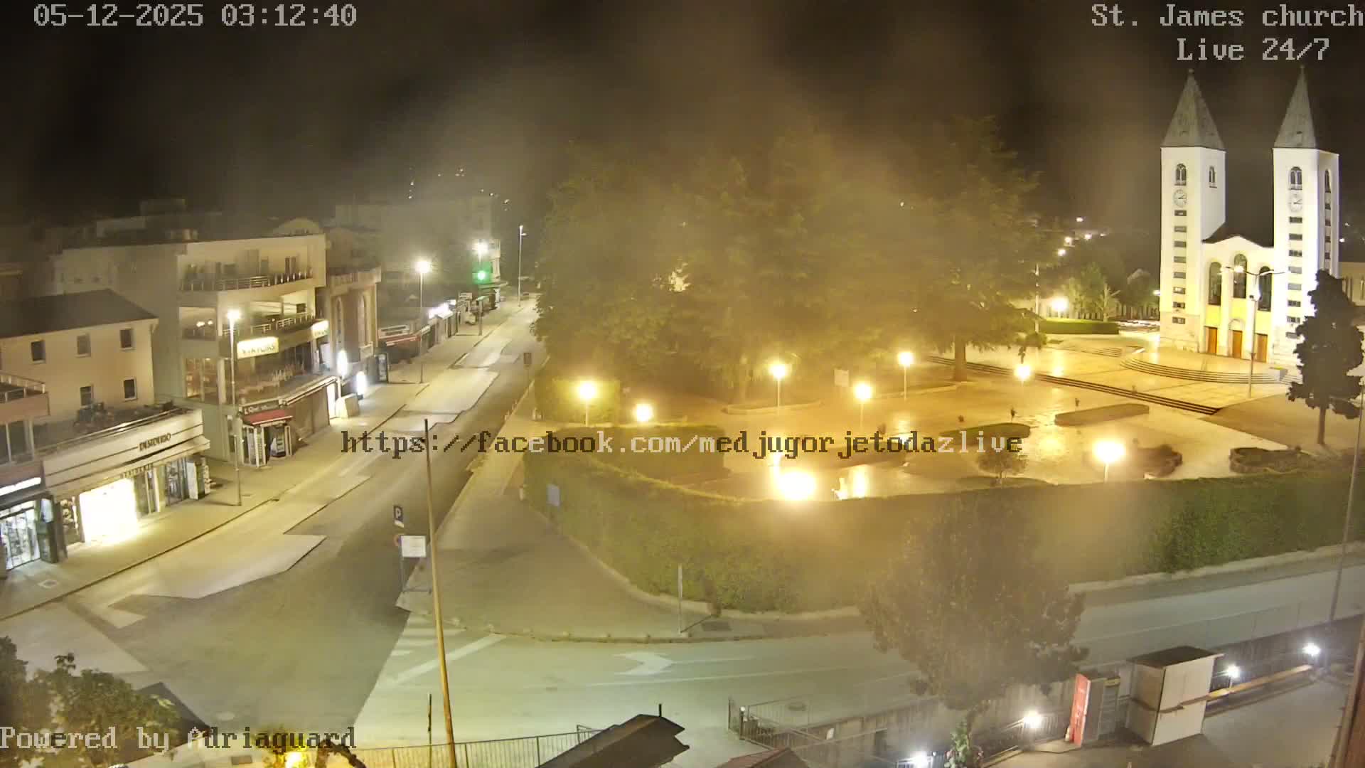 A nighttime, hazy view of a town square with a church, buildings, and streets.
