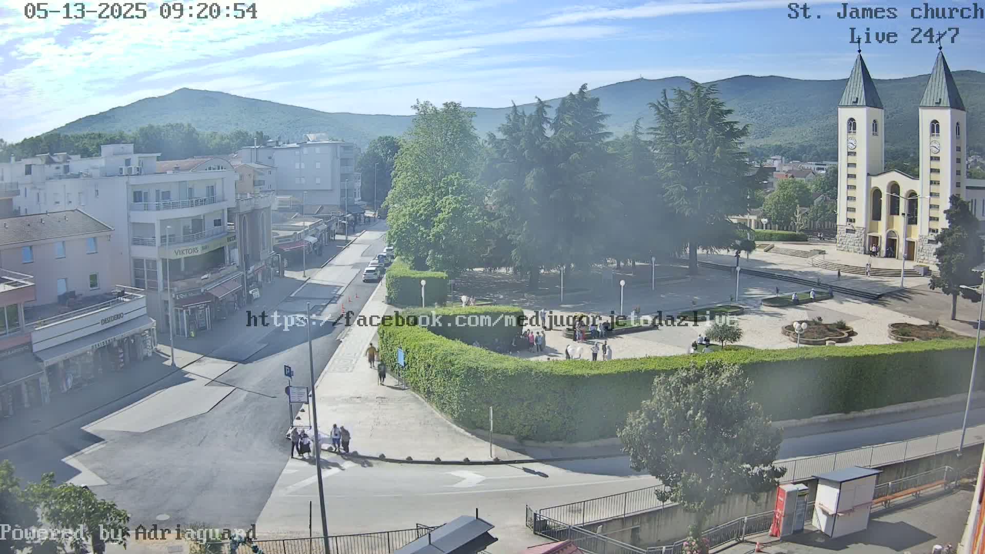 A hazy, sunny day overlooking a town square with a large church, surrounded by buildings and green spaces.