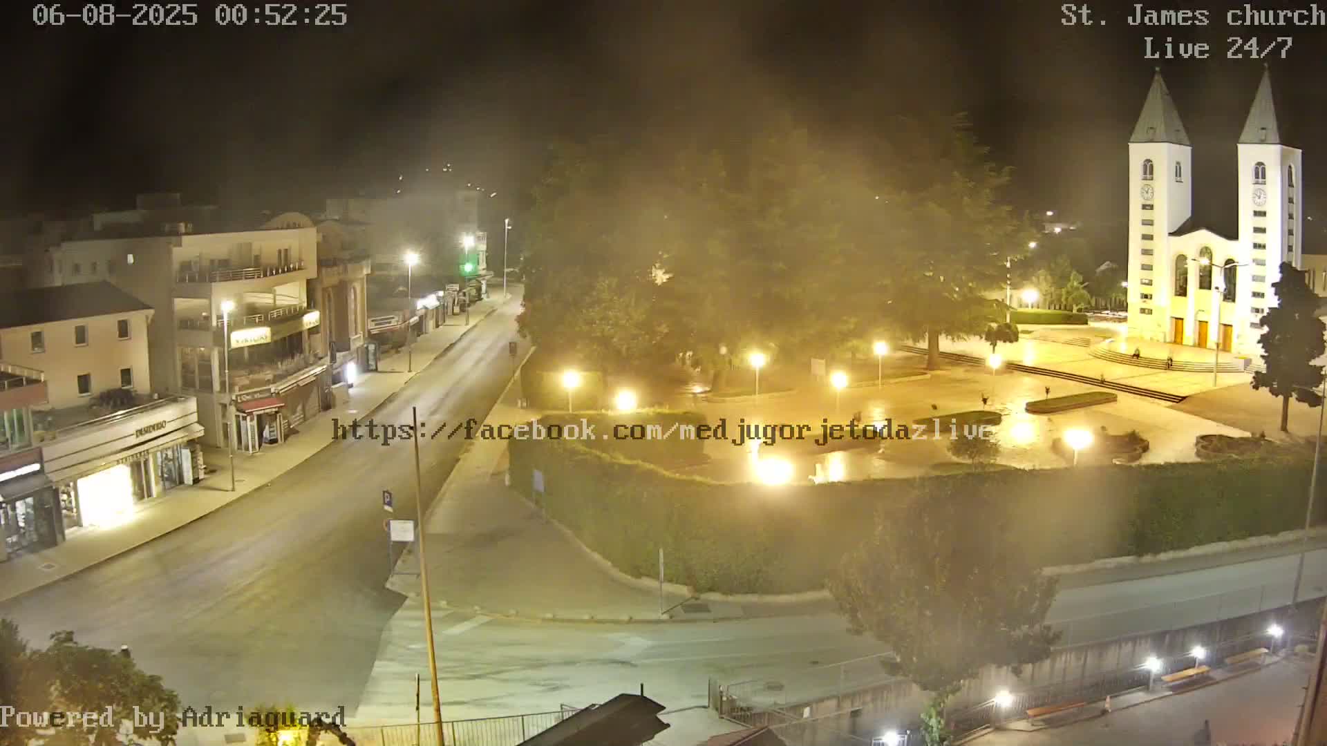 A nighttime, hazy view of a town square with a church at the far end, illuminated by streetlights.