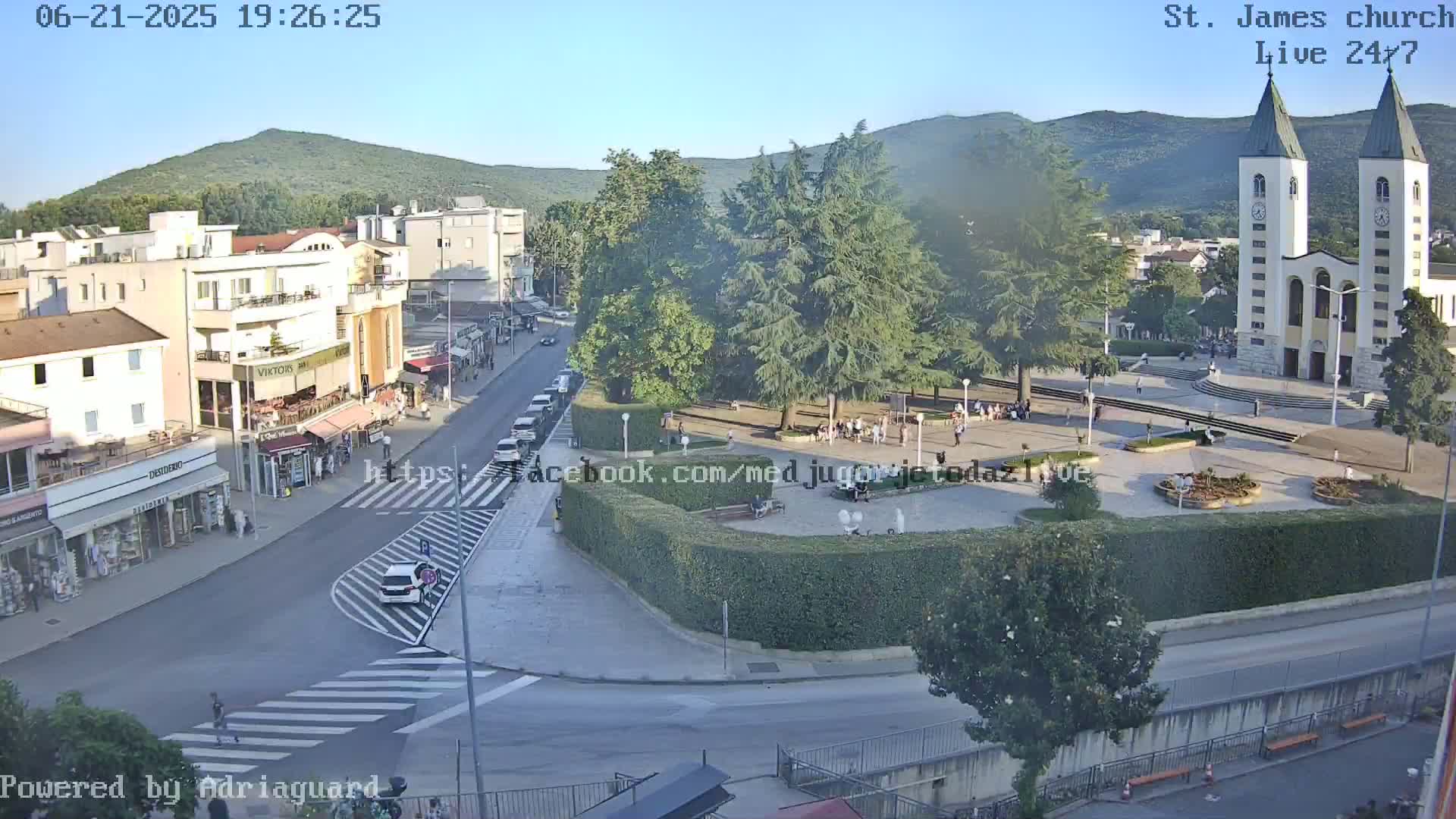 A high-angle, long shot of a town square with a church at sunset, under clear skies.