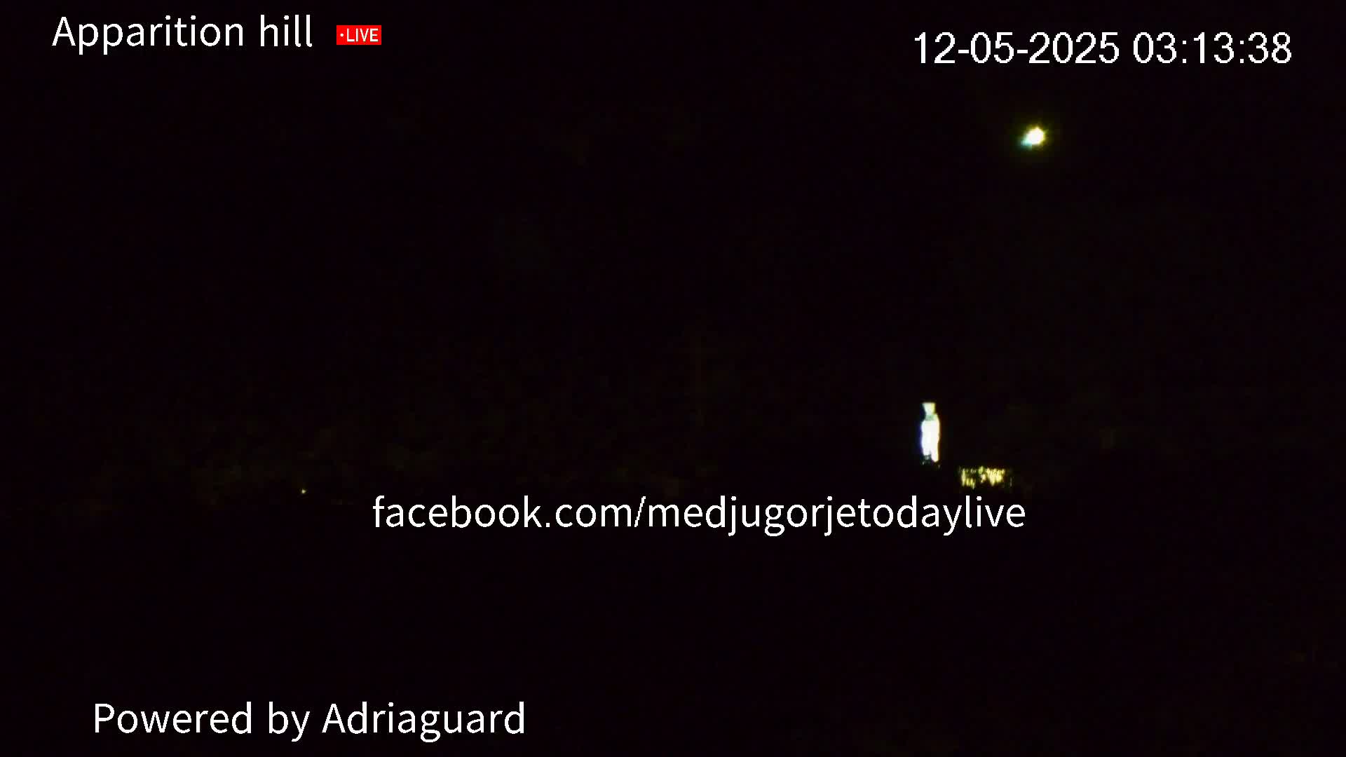 A dimly lit nighttime scene shows a small, bright light in the distance and a faint, taller light closer to the camera.