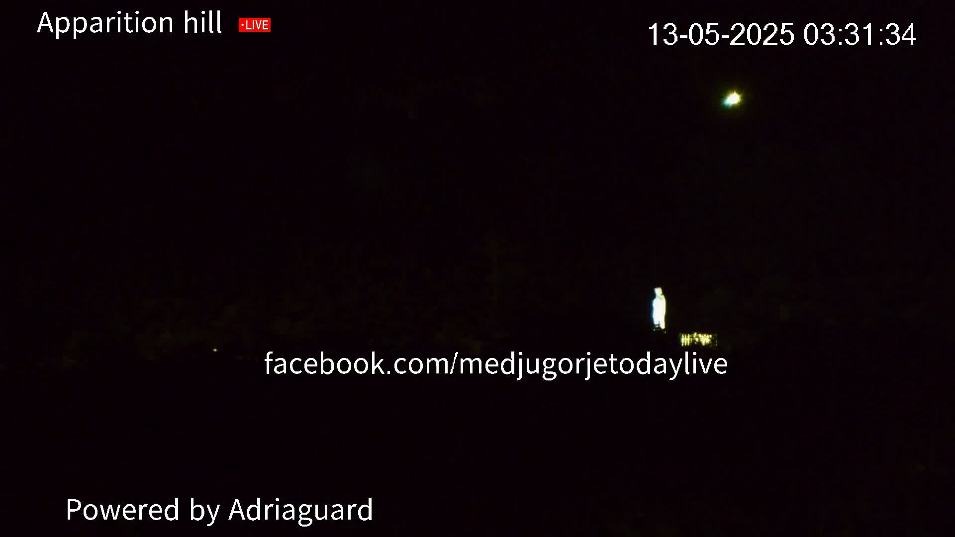 A dimly lit figure stands on a hill at night under a dark sky with a single bright light visible in the distance.