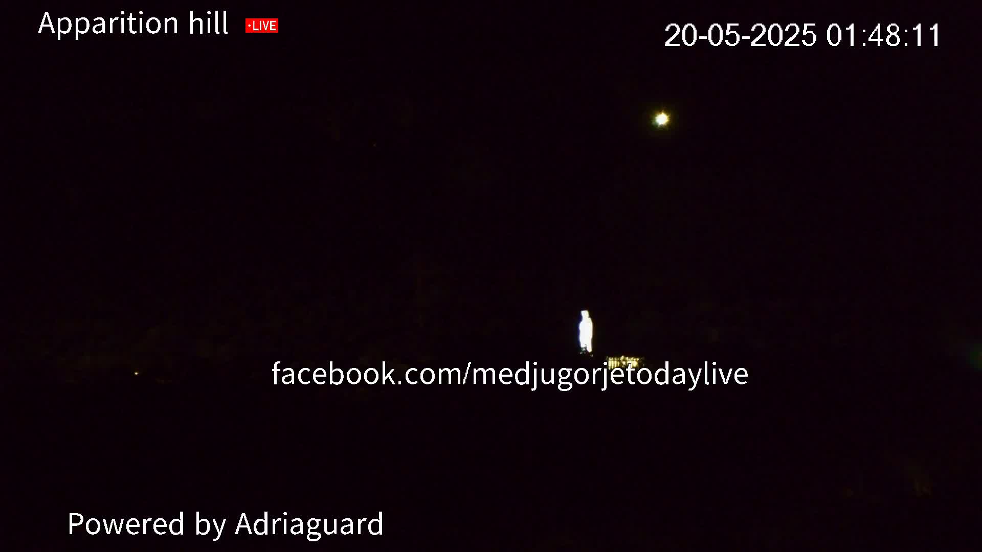 A brightly lit figure stands on a dark hill under a clear, nighttime sky with a single, bright star visible.