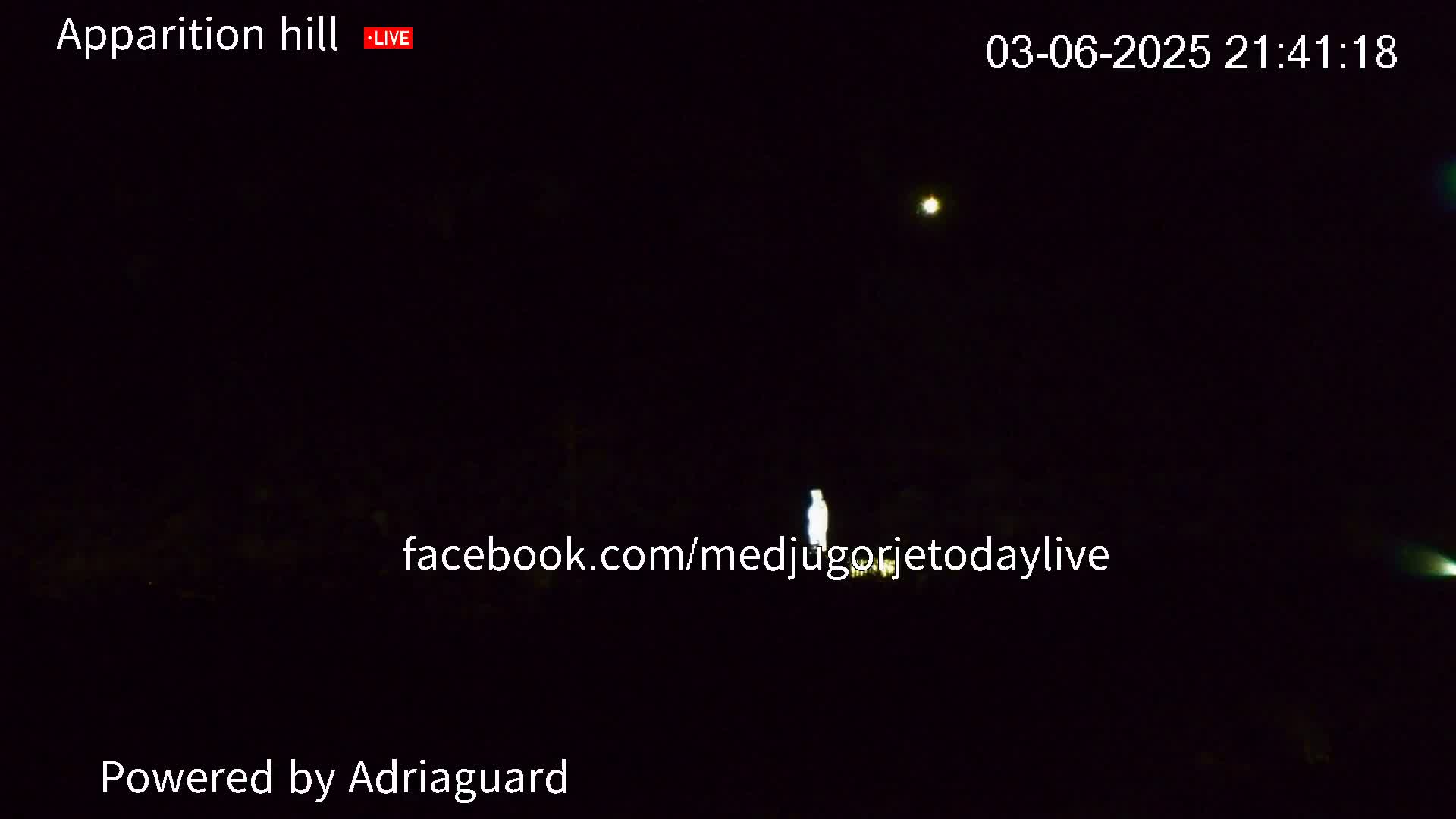 A dimly lit nighttime scene shows a faintly glowing figure in the center, with two brighter lights visible in the sky.