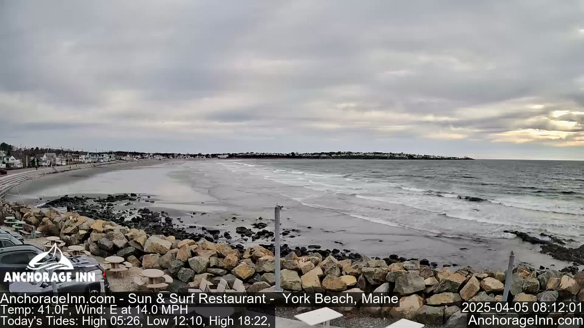 A beach with a rocky shoreline and calm waves under an overcast sky.
