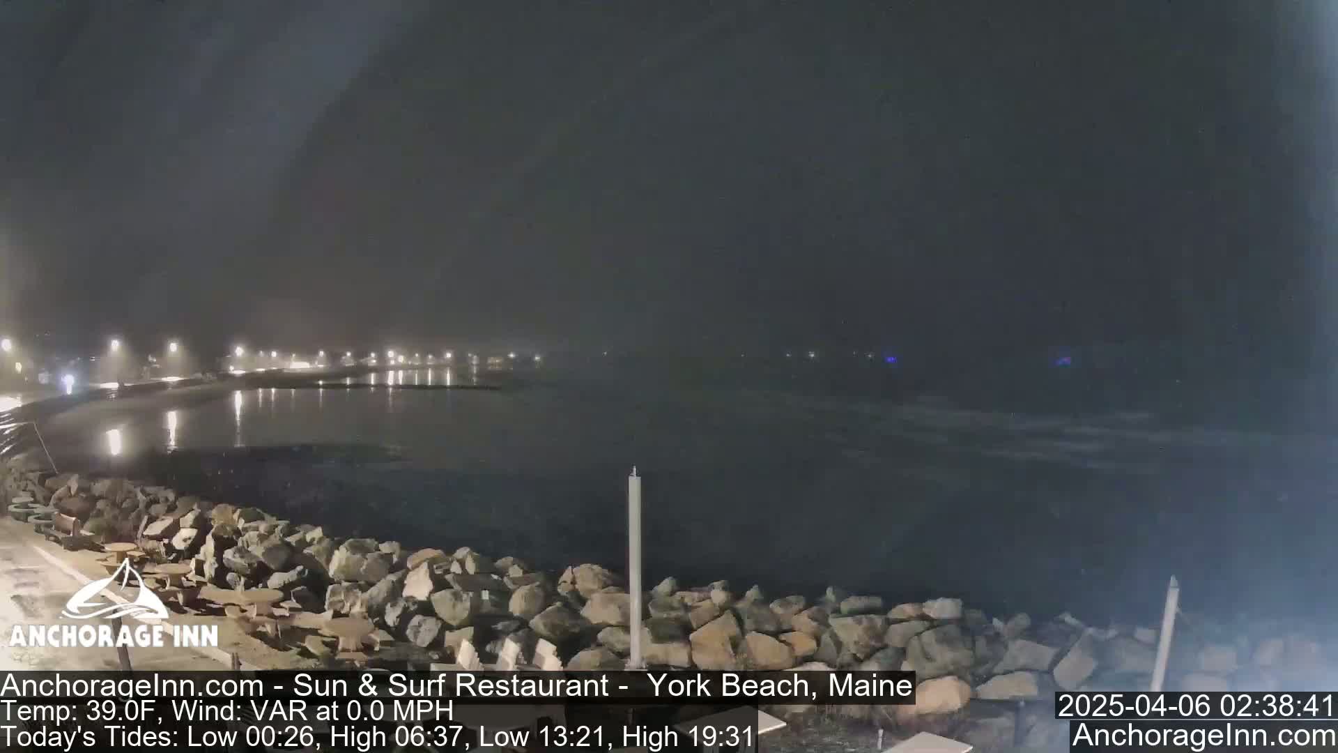 A nighttime view of a dark, calm body of water, faintly lit by distant lights and shrouded in a hazy atmosphere.