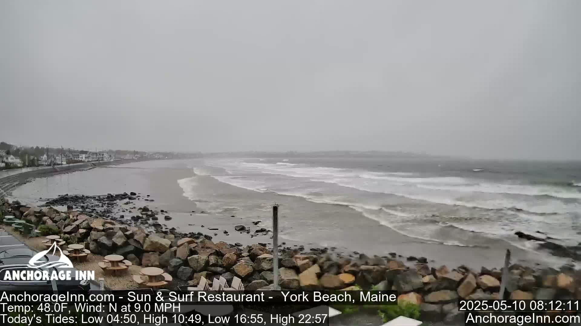 A rocky shoreline with waves rolling onto a beach on an overcast day.