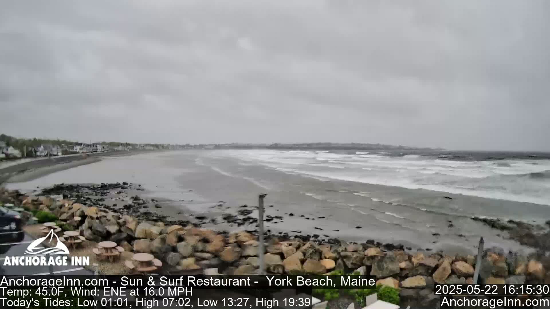 A rocky shoreline with a beach and choppy waves under an overcast sky.