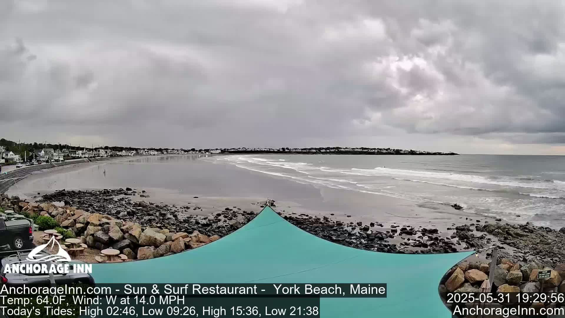 A beach with a rocky shoreline and calm waves stretches out under an overcast sky.