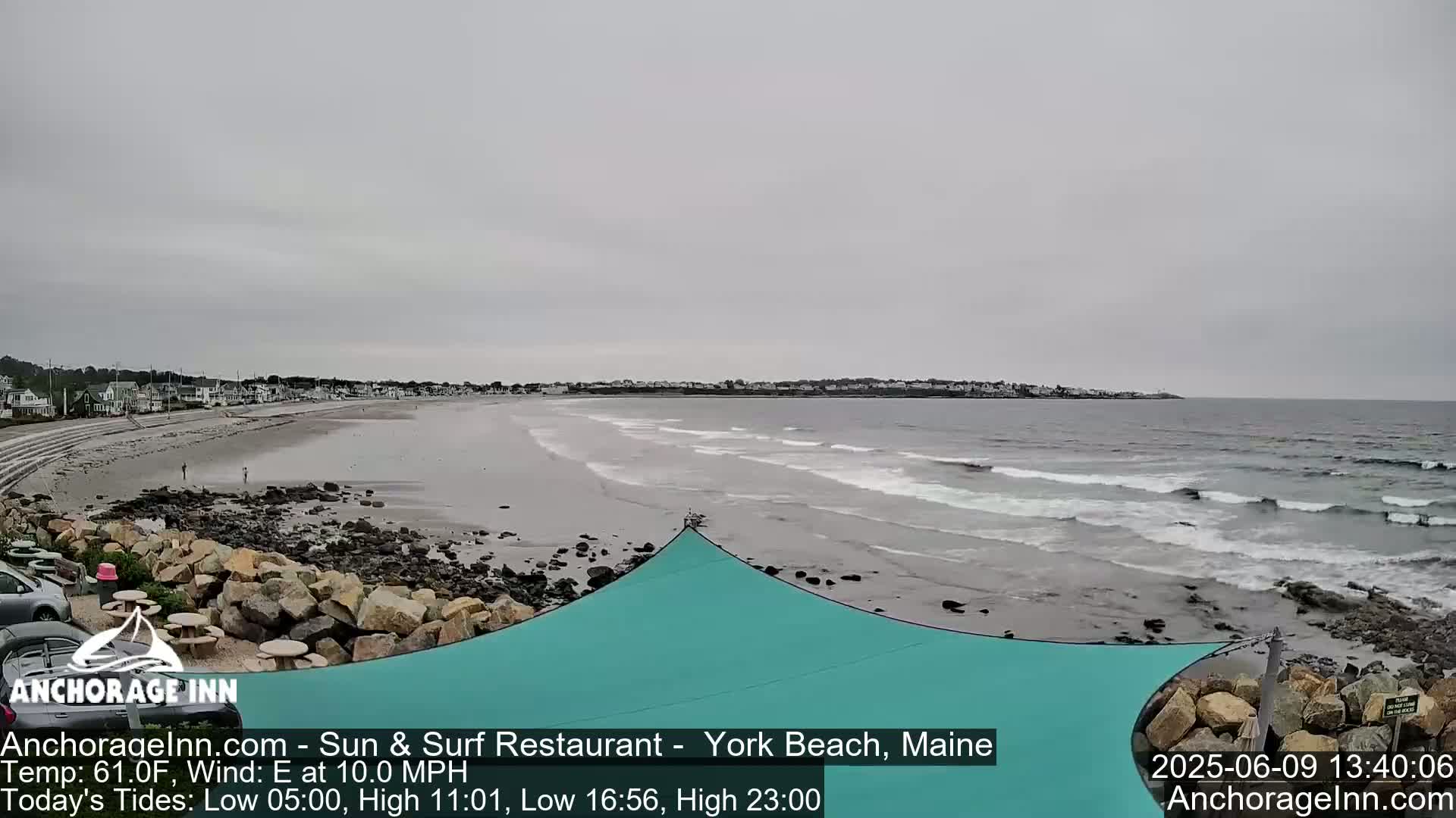 A wide shot of a beach with small waves lapping the shore under an overcast sky.