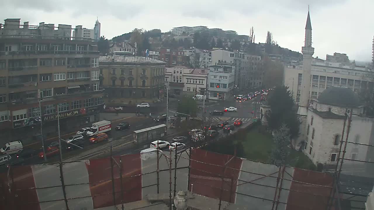 A nighttime, city street scene shows a multi-lane road with sparse traffic, buildings, and a minaret lit up next to a building.