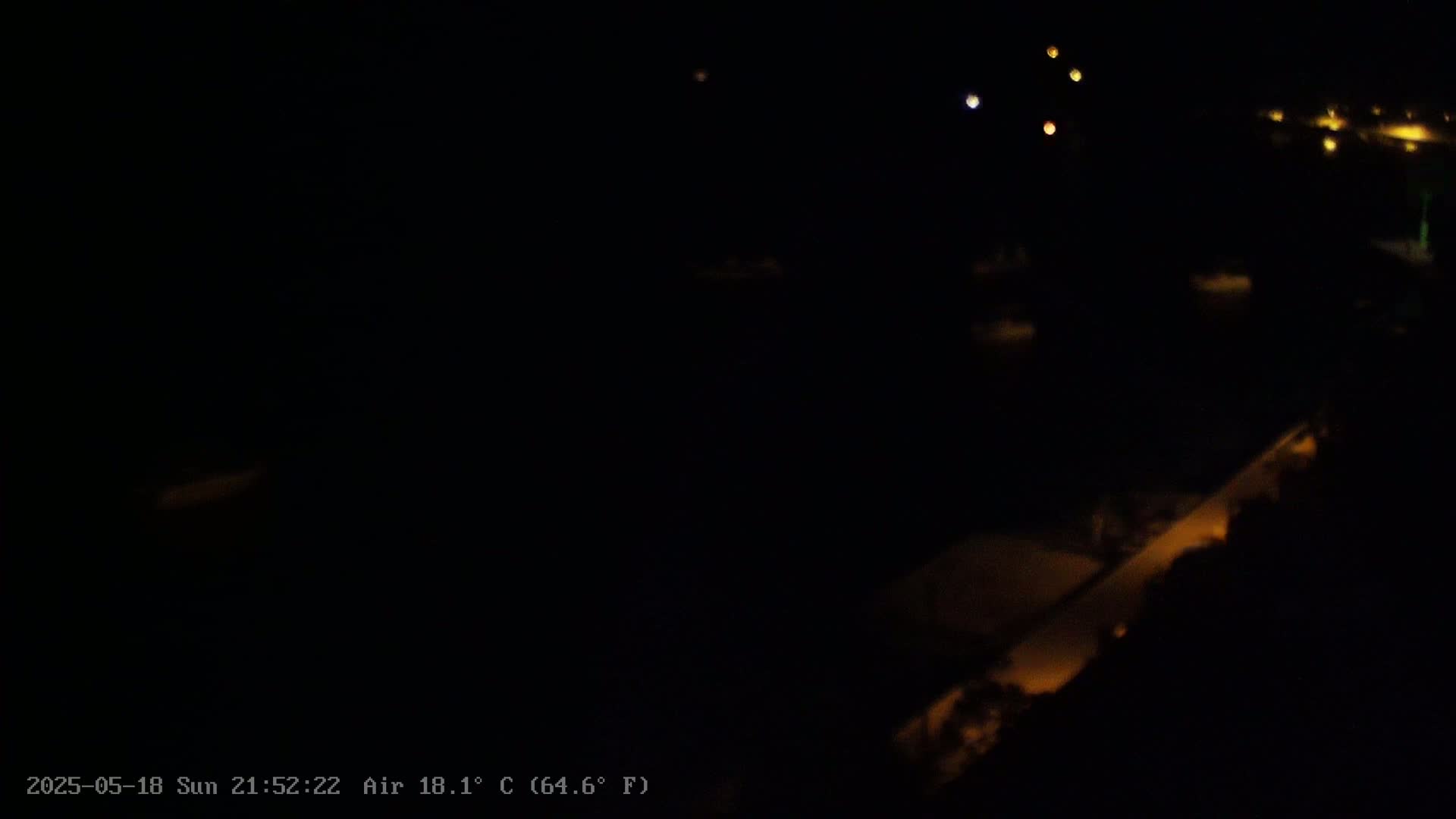 A dark, nighttime scene shows faintly lit areas of land and water, under a clear sky.
