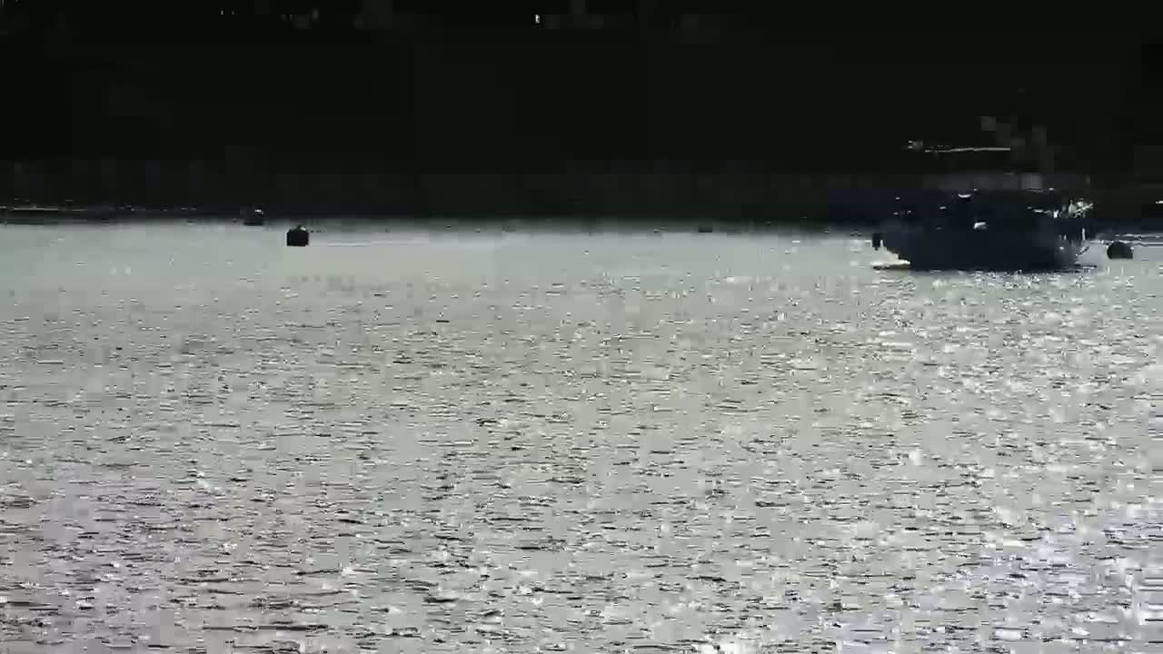 A boat is on a body of water that is slightly choppy under a bright, sunny sky.