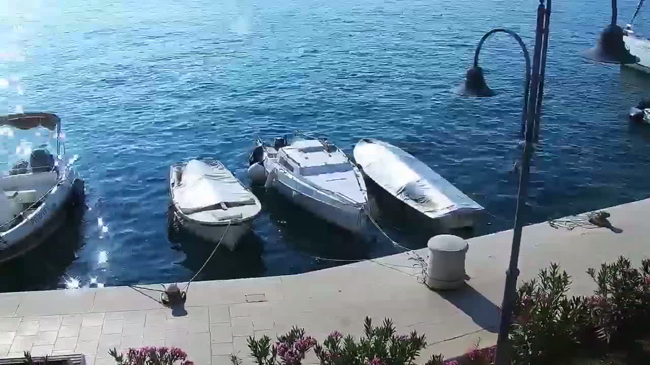 Three boats are moored at a dock on a calm, sunny day.