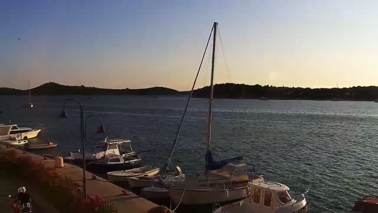 Several boats are moored along a waterfront at sunset under a clear sky.