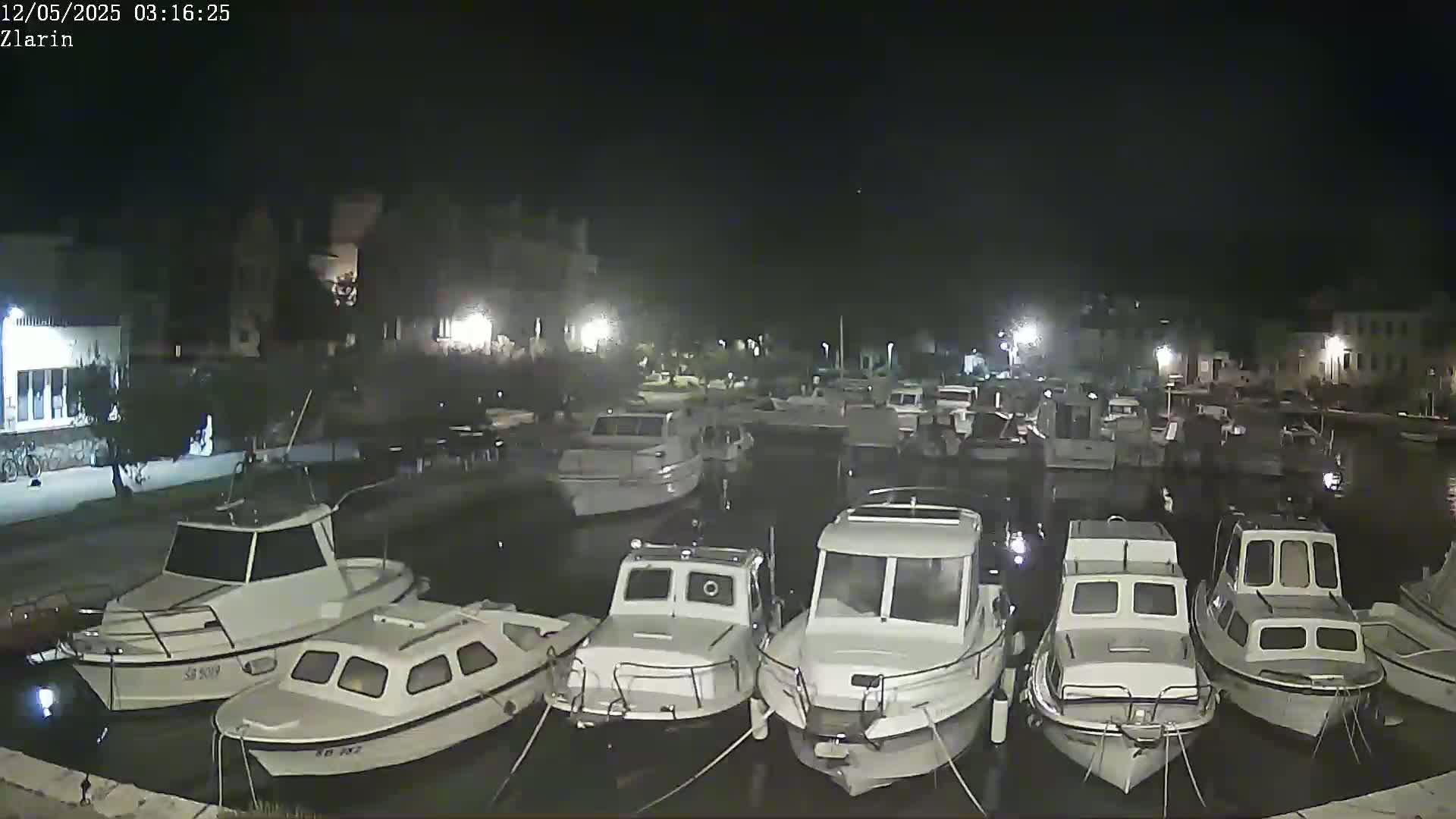 A nighttime view of a marina filled with numerous docked motorboats under a clear, dark sky.
