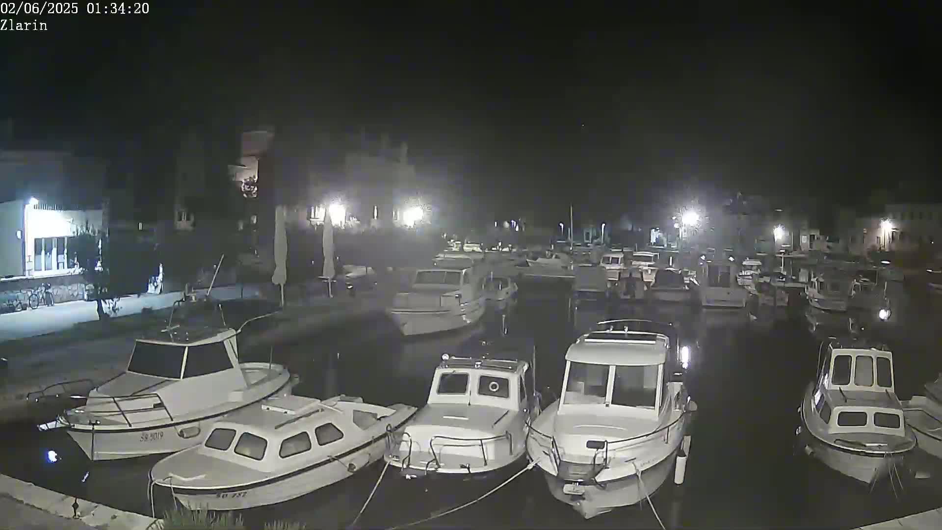 Several small white motorboats are docked at a marina at night.