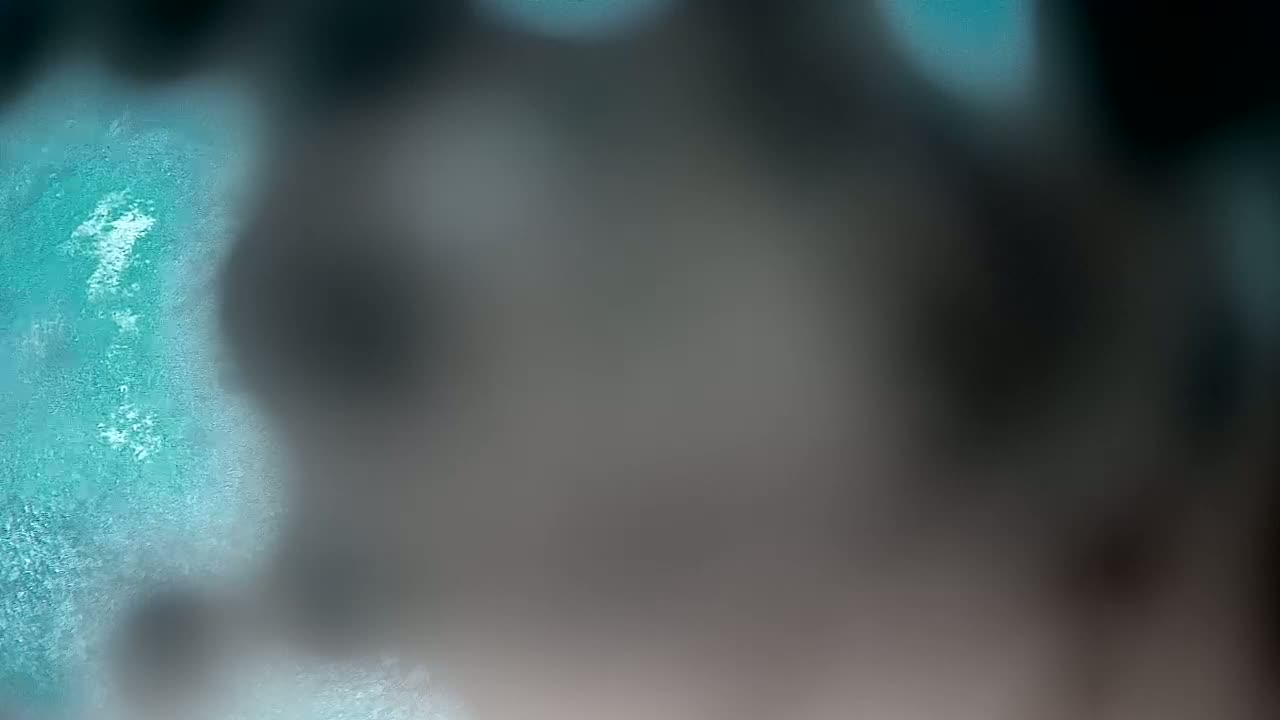 A blurry image shows a teal surface with a darker, out-of-focus area obscuring part of it.