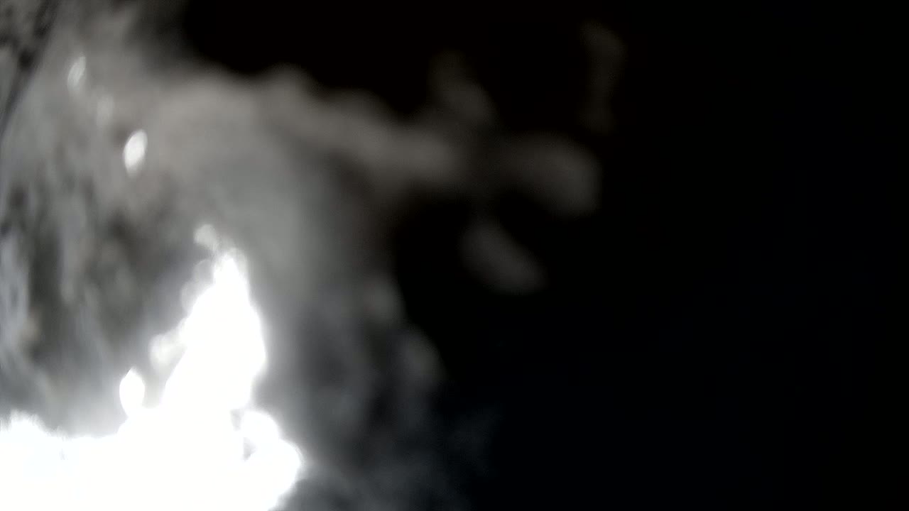 A bright, blurry light source is partially obscured by thick, white smoke against a dark background.