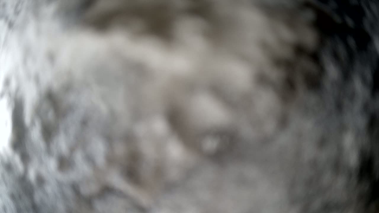 A blurry, out-of-focus image shows a swirling mass of gray and white, resembling smoke or clouds.