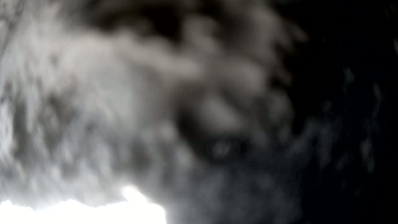 A blurry image shows dark gray and white clouds filling the frame, with a bright area visible at the bottom.