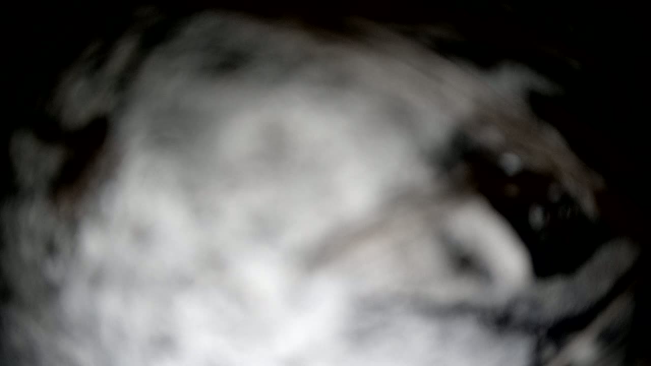 A blurry, out-of-focus image shows a swirling mass of gray and white, resembling smoke or fog.