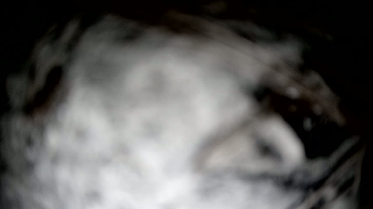 A blurry, out-of-focus image shows swirling shades of gray and black, resembling smoke or fog.