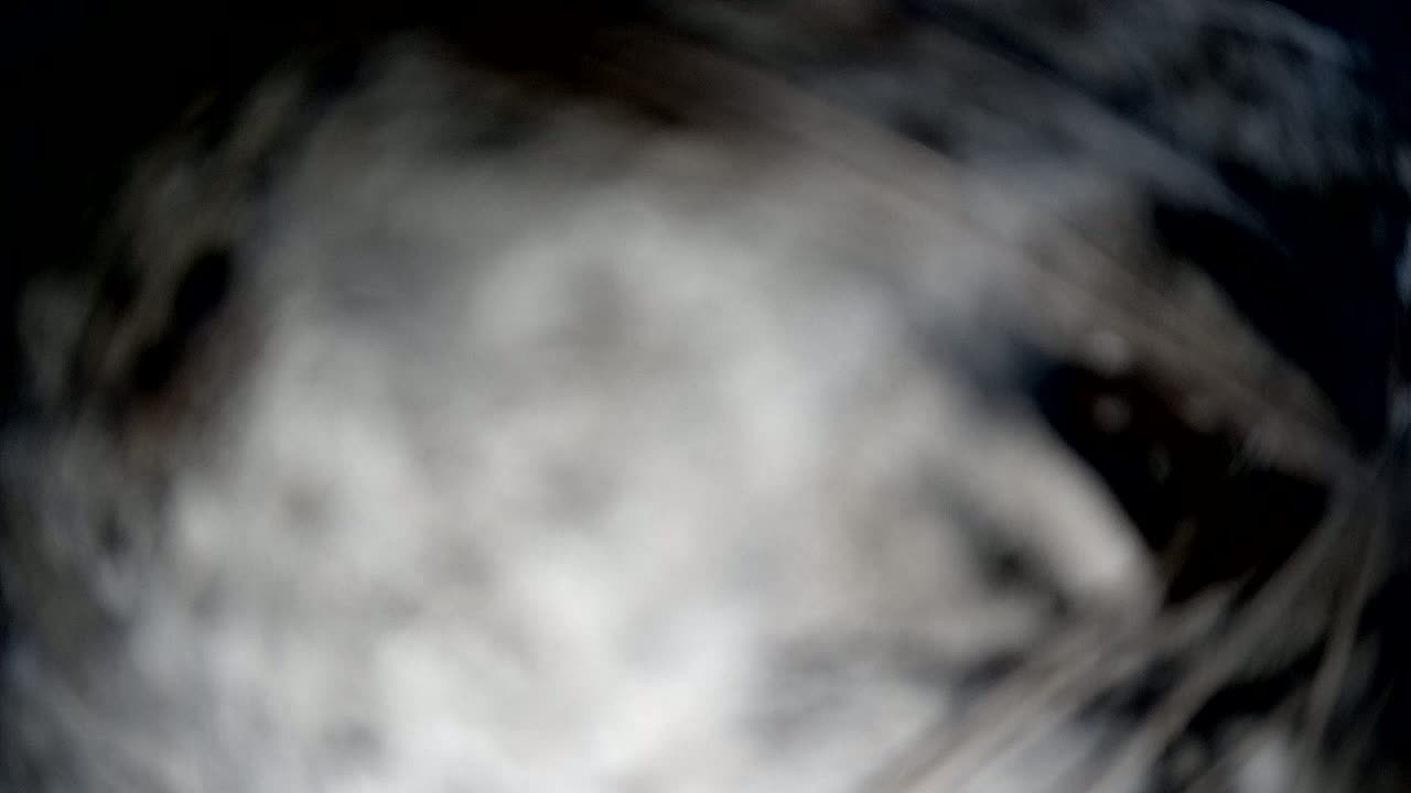A blurry, out-of-focus image shows swirling shades of gray and black, resembling smoke or fog.