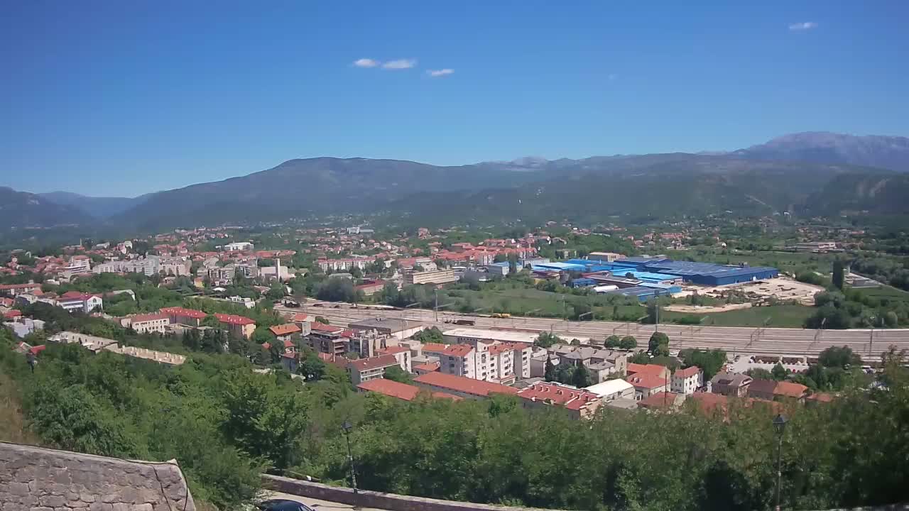 A sprawling town nestled in a valley between mountains under a clear blue sky.