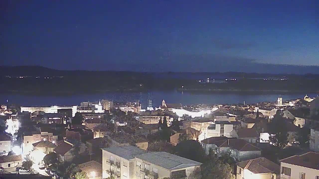 A nighttime view of a town situated on a waterfront, under a clear, dark sky.