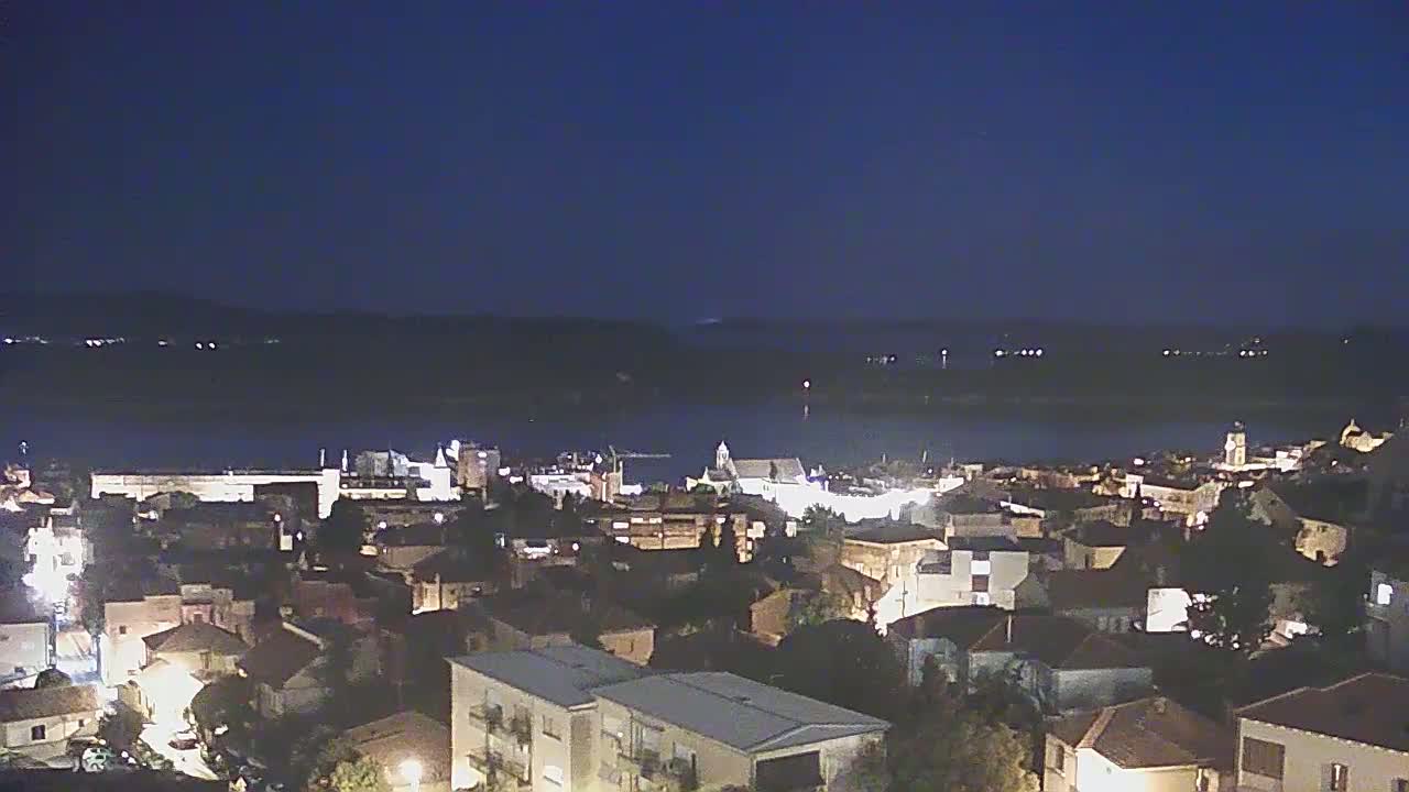 A nighttime view of a town situated near a body of water under a clear, dark sky.