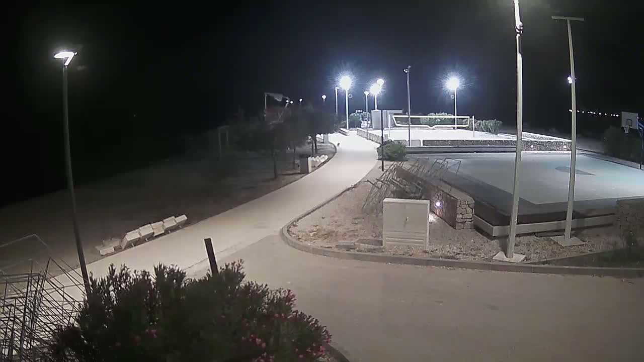 A well-lit outdoor basketball court and walkway are visible at night.