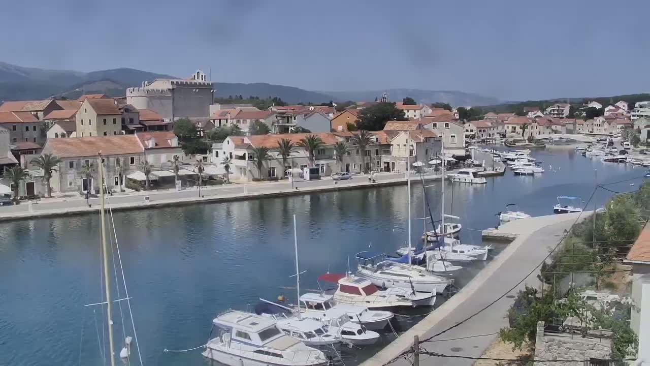 A waterfront town with numerous boats docked in a calm harbor under a clear blue sky.