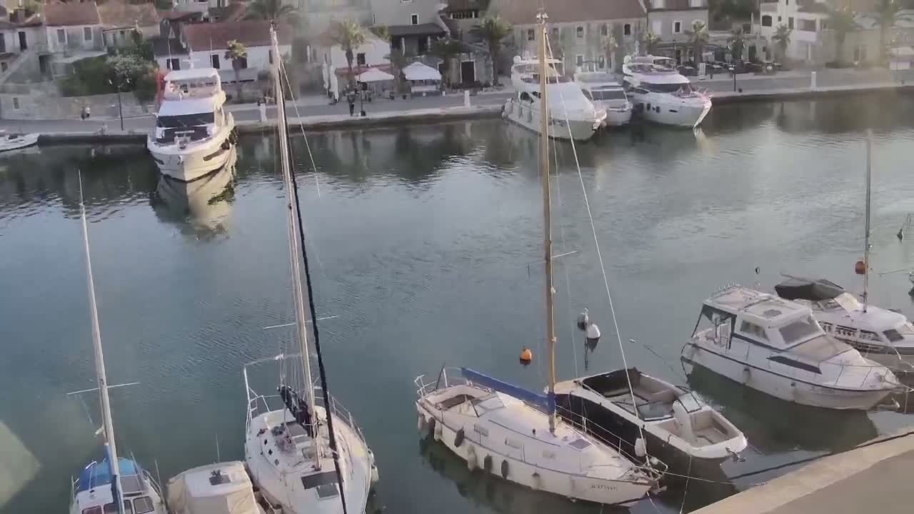 A calm harbor filled with sailboats and motorboats is nestled next to a waterfront town.