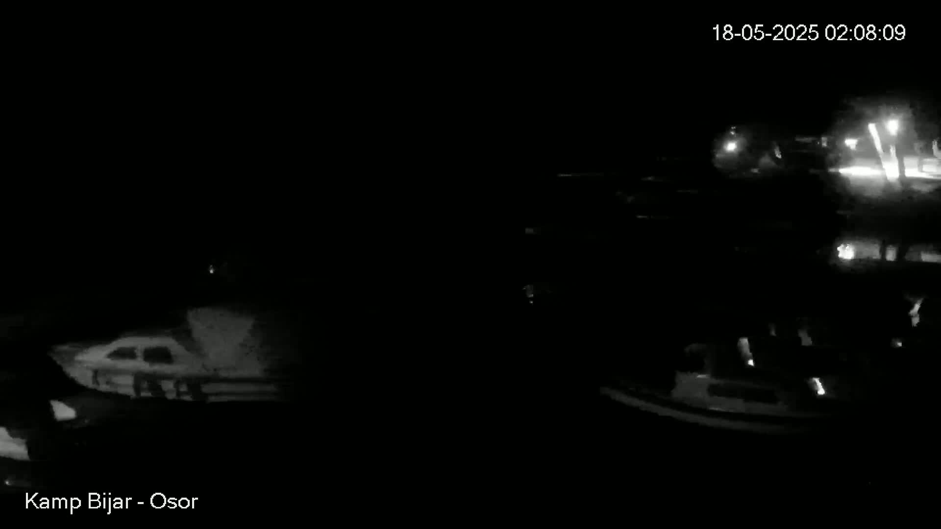 A nighttime, low-light image shows two boats docked at a marina.
