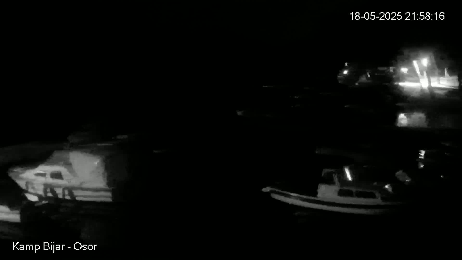 Several boats are moored at a dock at night.