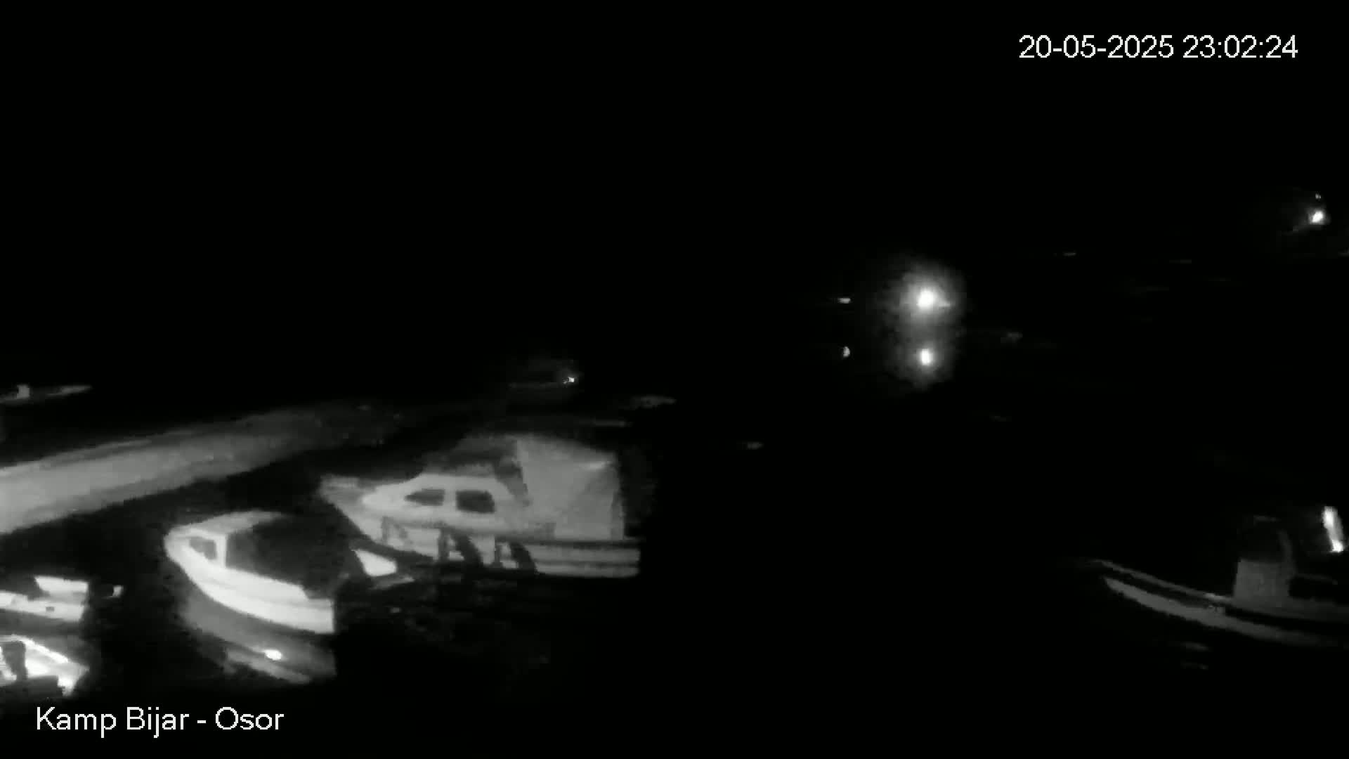 Several boats are moored in a dark, nighttime harbor.