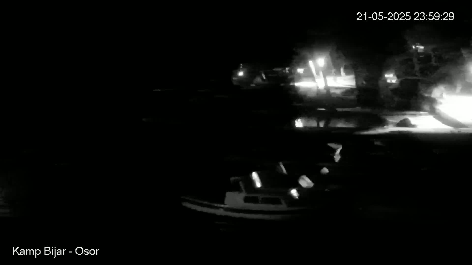 A nighttime, low-light image shows several boats moored at a dock.