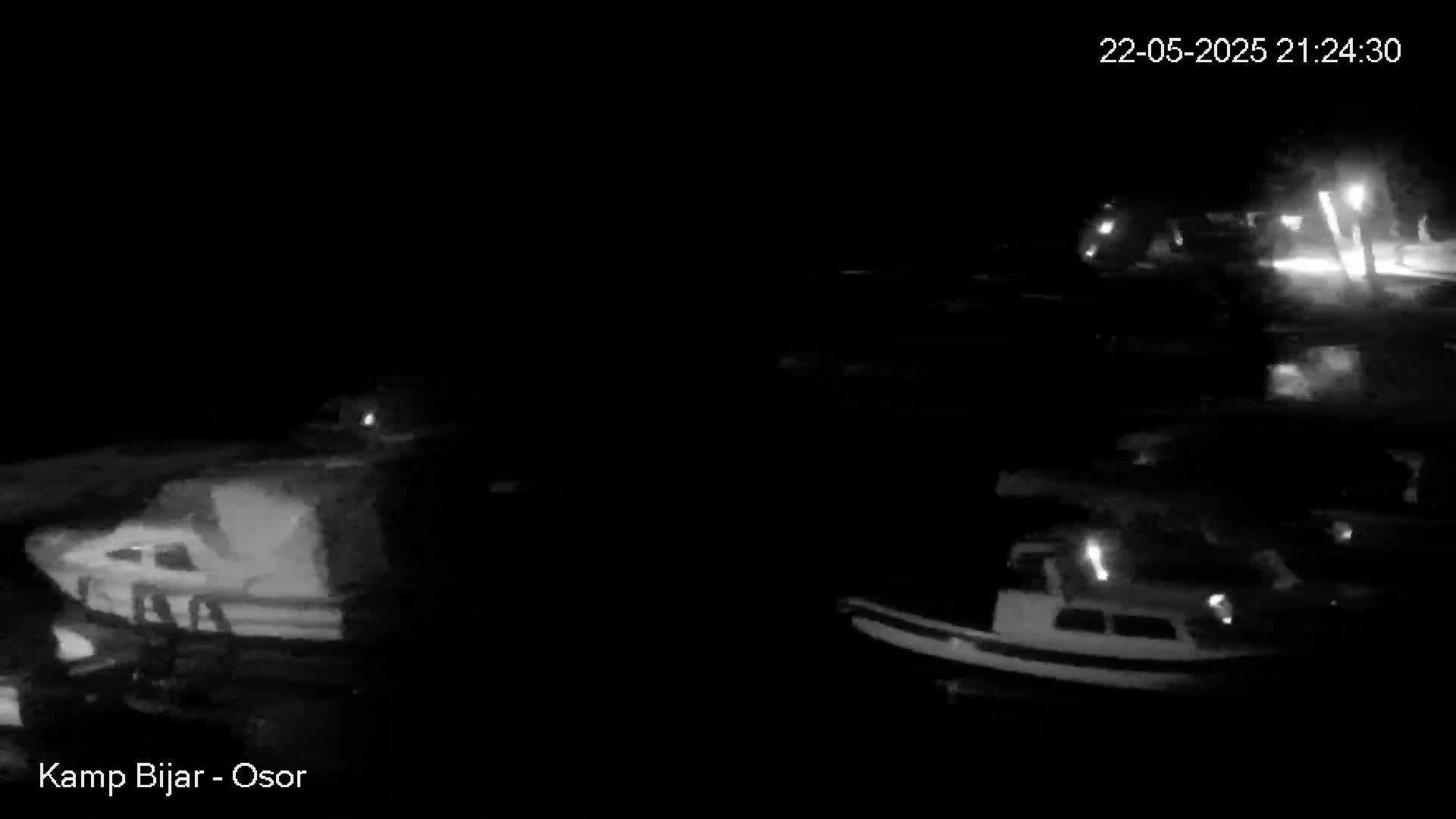 Several boats are moored in a dark, calm body of water at night.