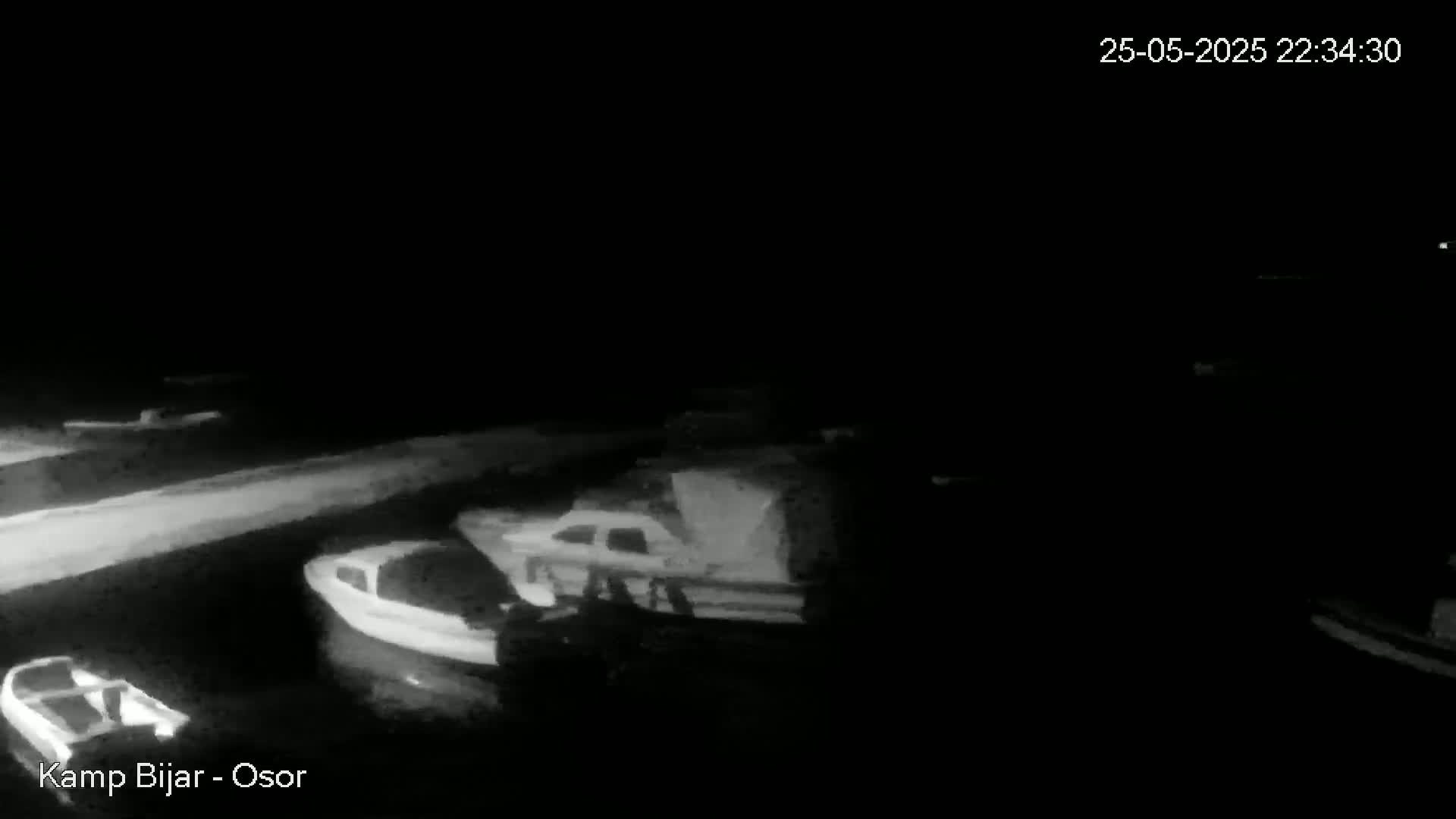 Several small boats are moored at a dock at night under a dark sky.