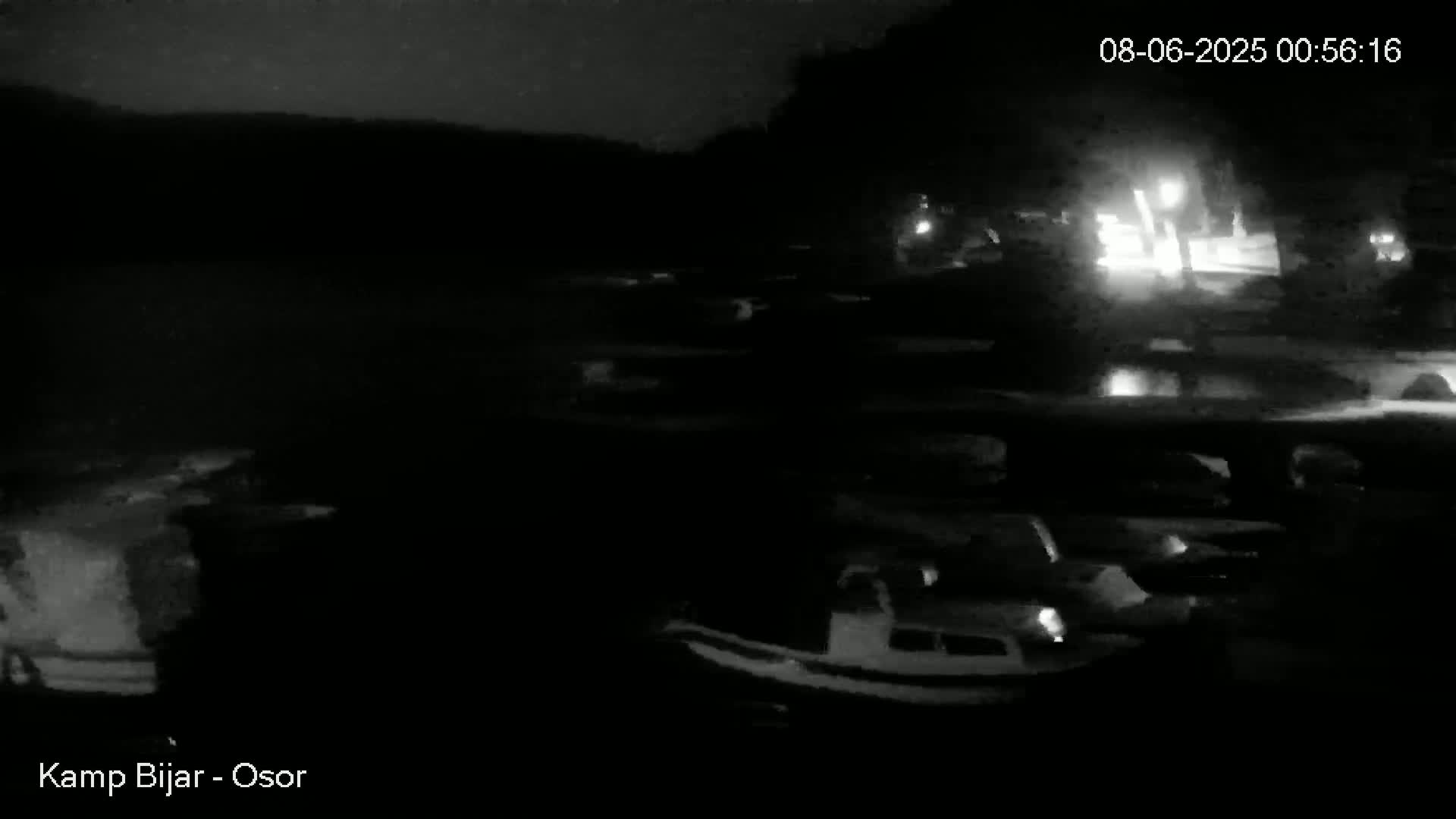 A nighttime, low-light view of a marina with numerous boats docked, illuminated by faint lights.