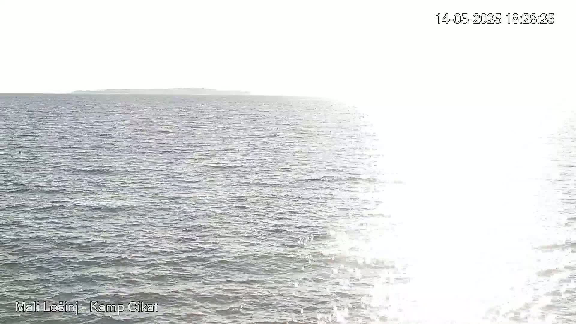A calm sea with a distant landmass visible on a bright, sunny day.