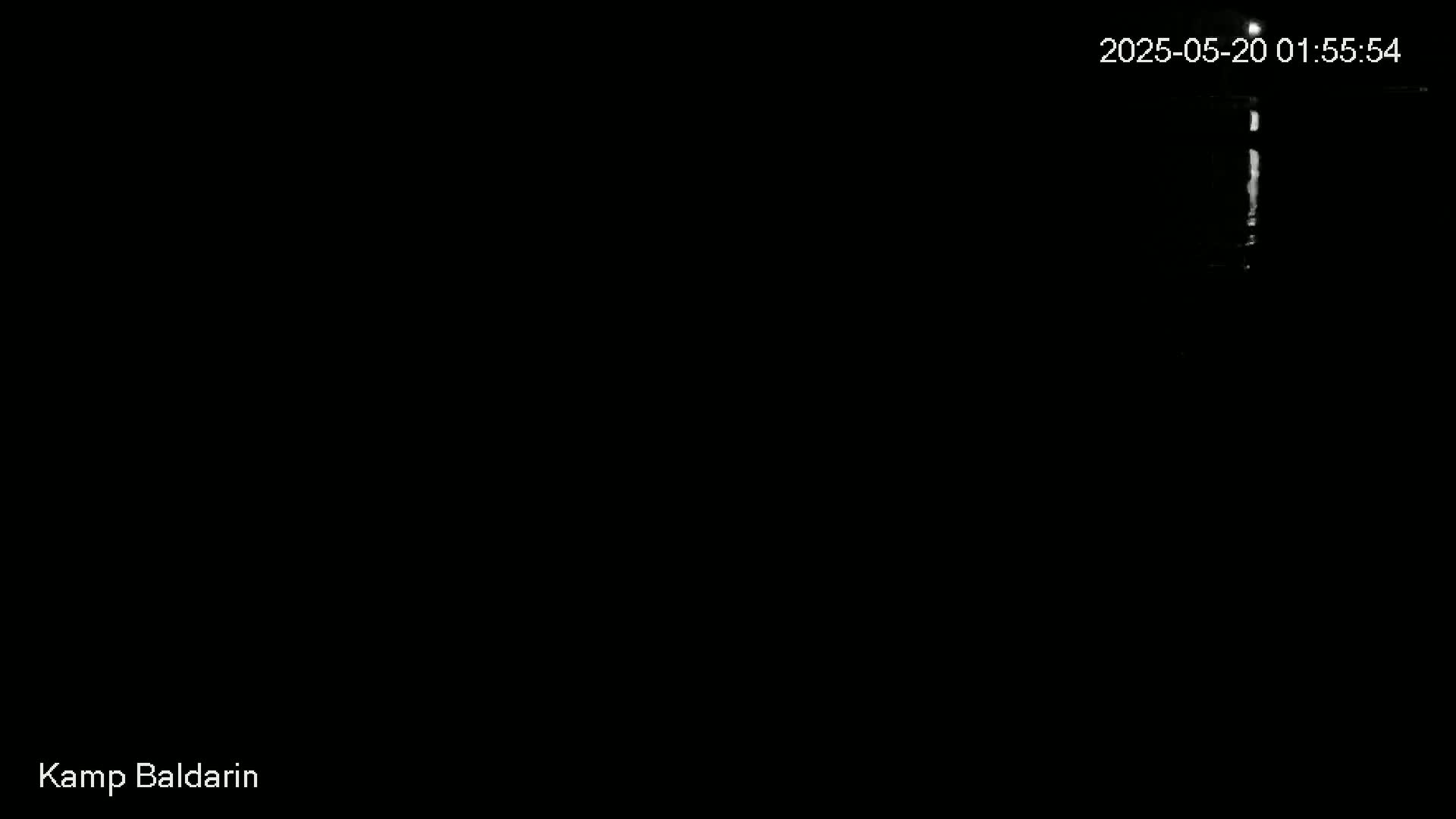 A dark, nighttime scene shows a faint, vertical light source in the center.