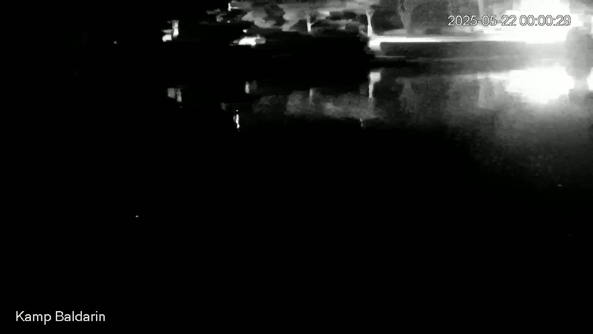 A nighttime, low-light image shows a dark body of water reflecting a blurry, indistinct shoreline.