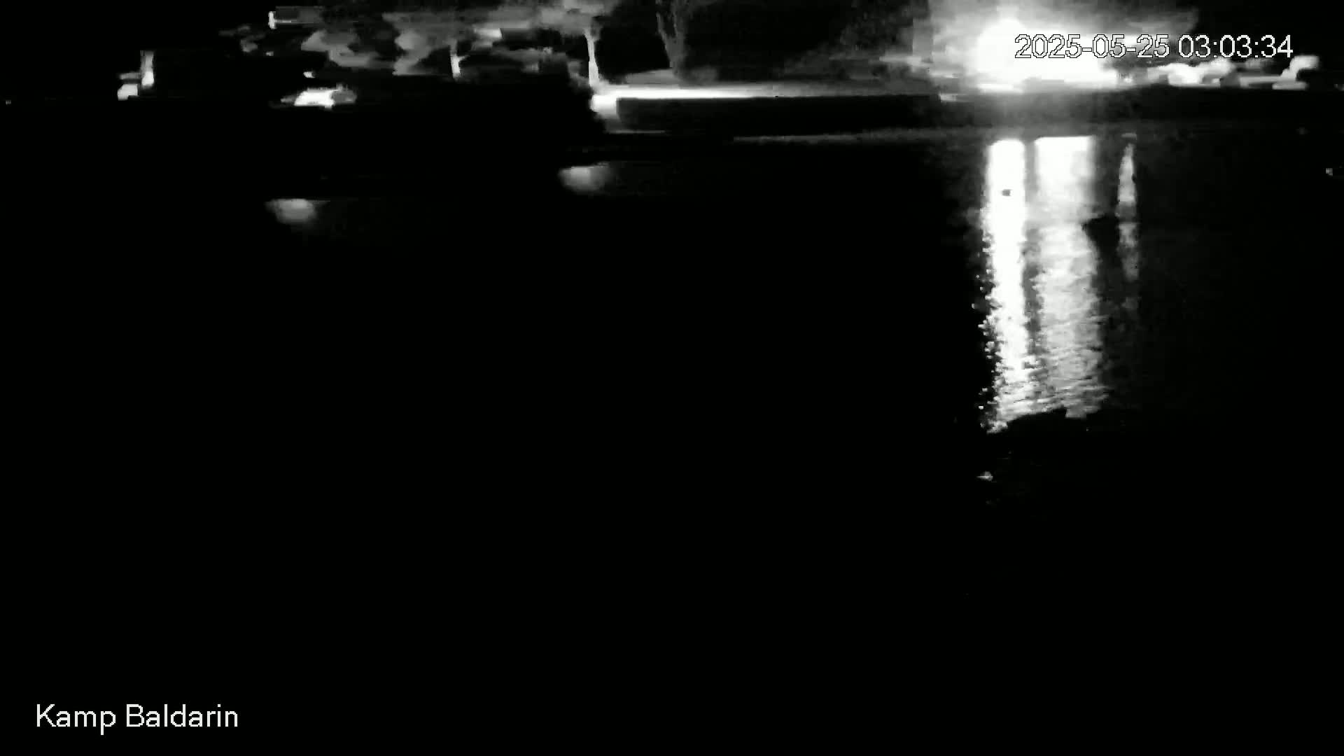 A nighttime, low-light view of a body of water reflecting lights from the opposite shore.