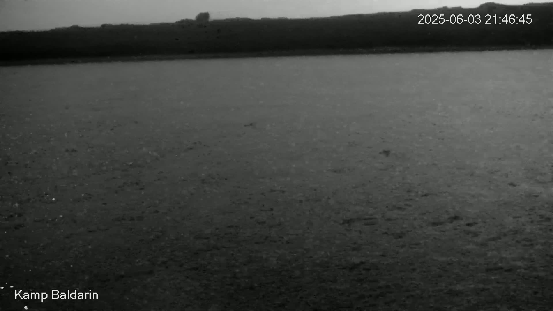 A dark, flat expanse of land extends to a distant, dark horizon under an overcast sky.