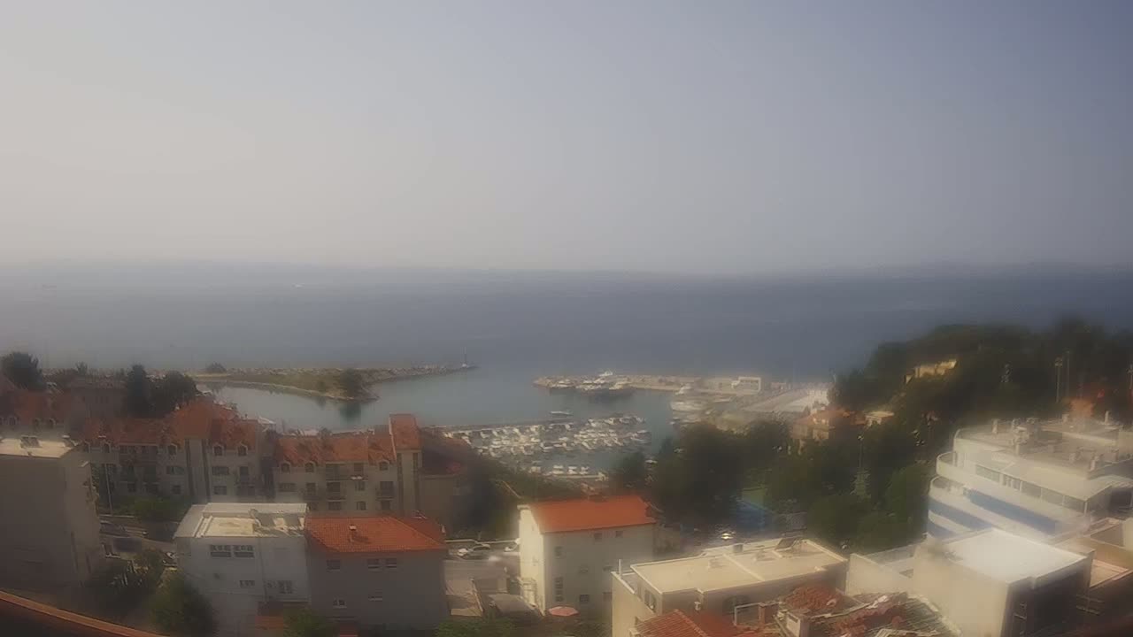 A hazy, sunny day overlooking a coastal town with a marina filled with boats.