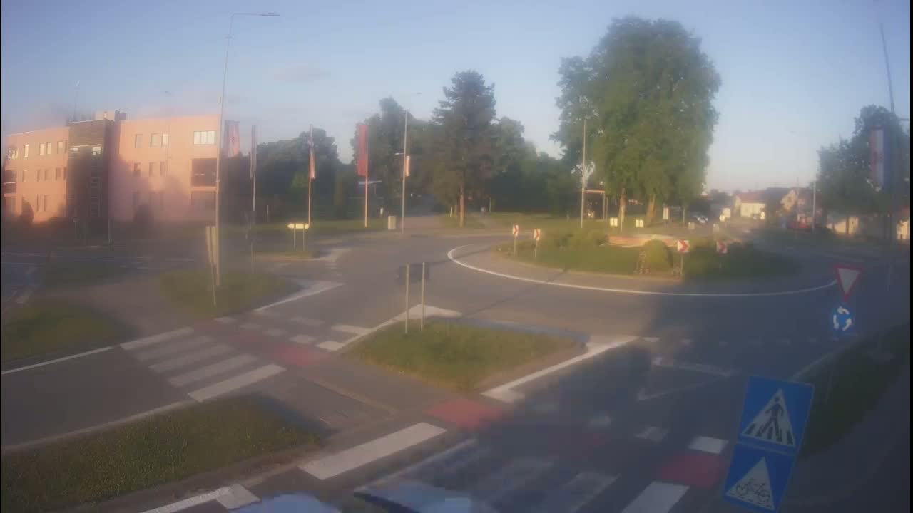 A roundabout with a pedestrian crossing and a multi-story building is visible in the hazy morning light.