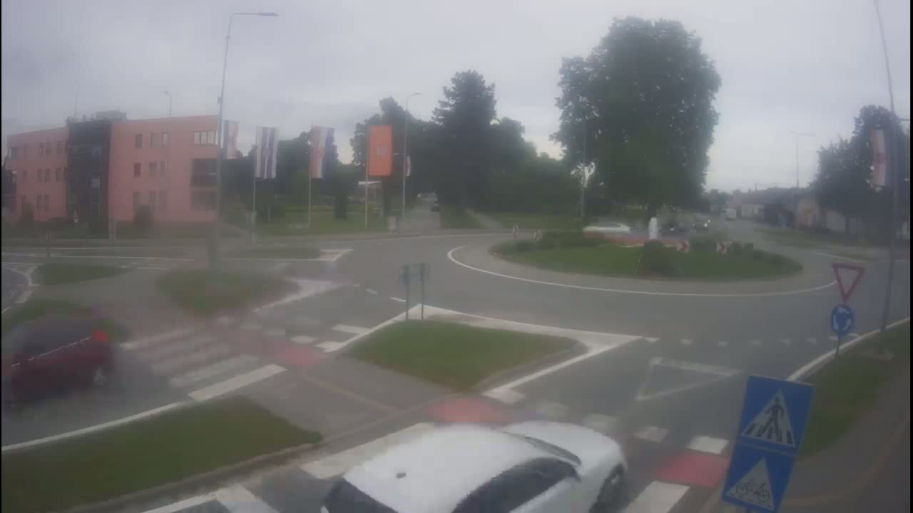 A roundabout with several cars is visible on an overcast day.